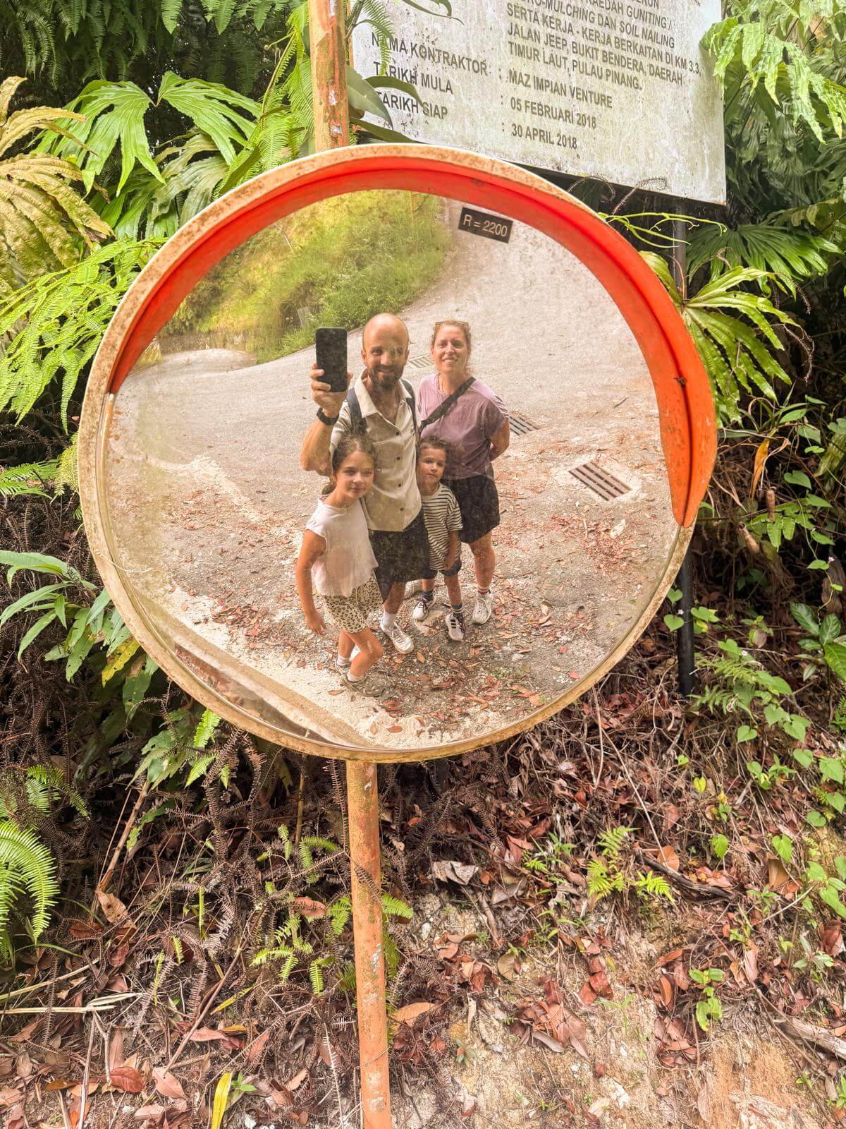 Gezinsselfie in een verkeersspiegel langs het bospad van Penang Hill