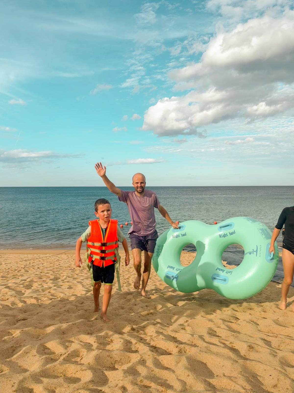 Papa en zoon met de opblaasbanden klaar voor de waterslide op het strand