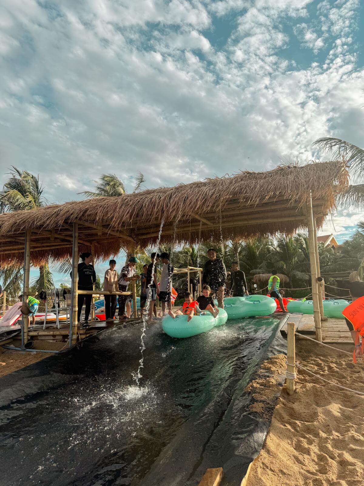 Kinderen razen samen naar beneden op de waterslide, met opspattend water