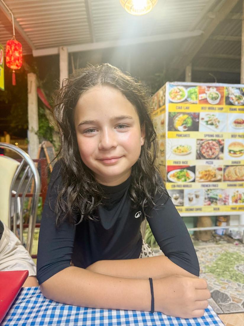 Ida bij een restaurantje in Hoi An, met het menu op het bord achter haar